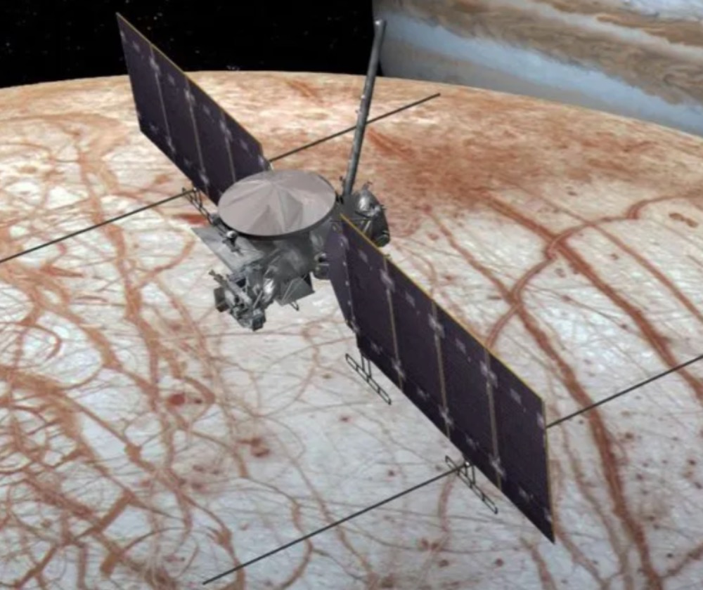 An illustration of the Europa Clipper over its icy moon target