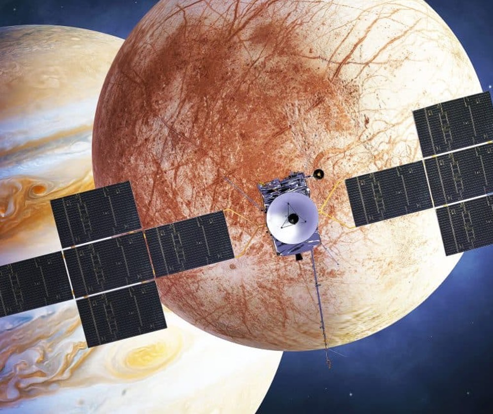 An illustration of the Europa Clipper over its icy moon target