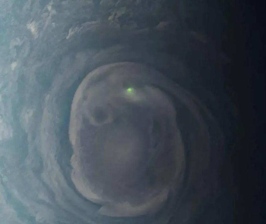 In this view of a vortex near Jupiter's north pole, NASA's Juno mission observed the glow from a bolt of lightning.