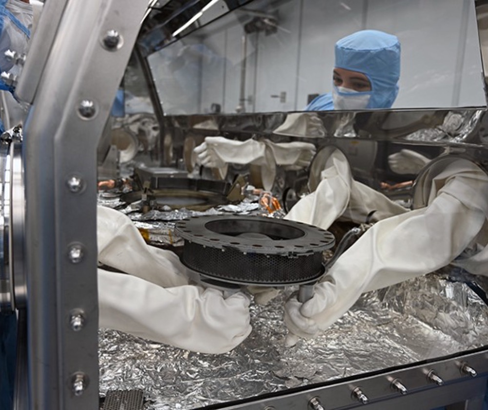 Researchers handle OSIRIS-REx’s sample canister inside a glovebox at the Johnson Space Center in Houston, Texas