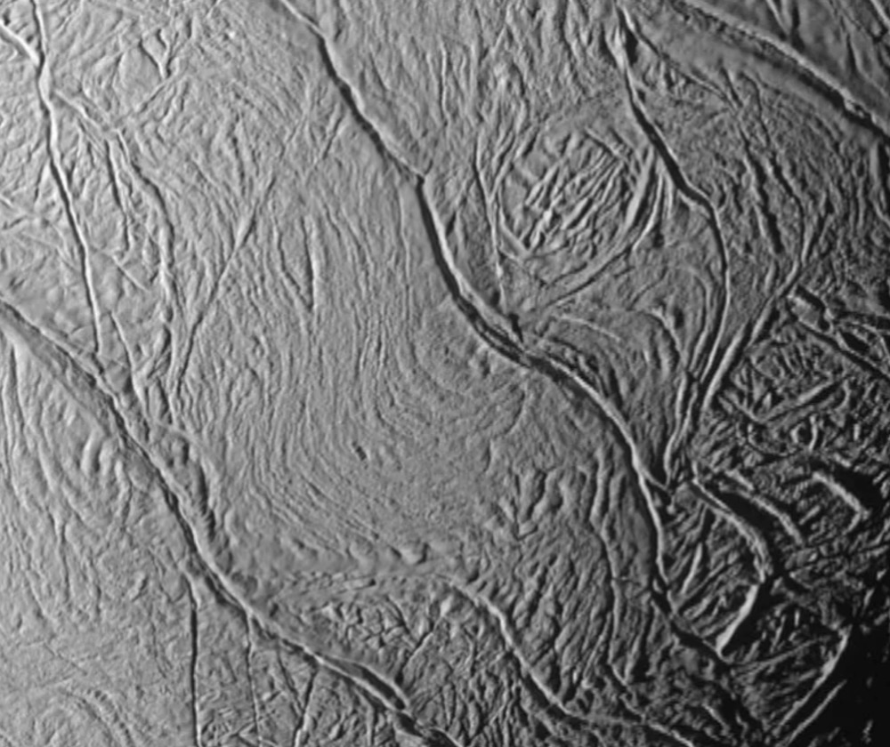 This close-up view of Saturn's moon Enceladus looks toward the moon's terminator (the transition from day to night) and shows a distinctive pattern of continuous, ridged, slightly curved and roughly parallel faults within the moon's southern polar latitudes