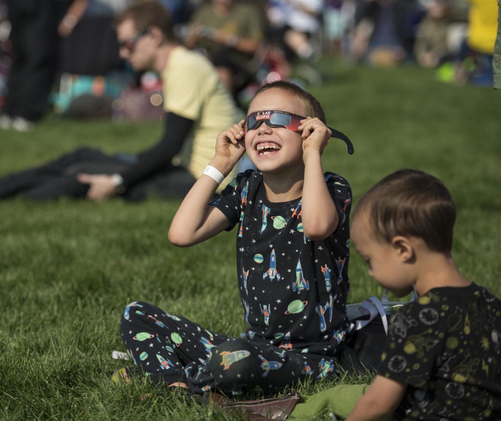 A boy watches the total solar eclipse through protective glasses in Madras, Oregon on Monday, Aug. 21, 2017