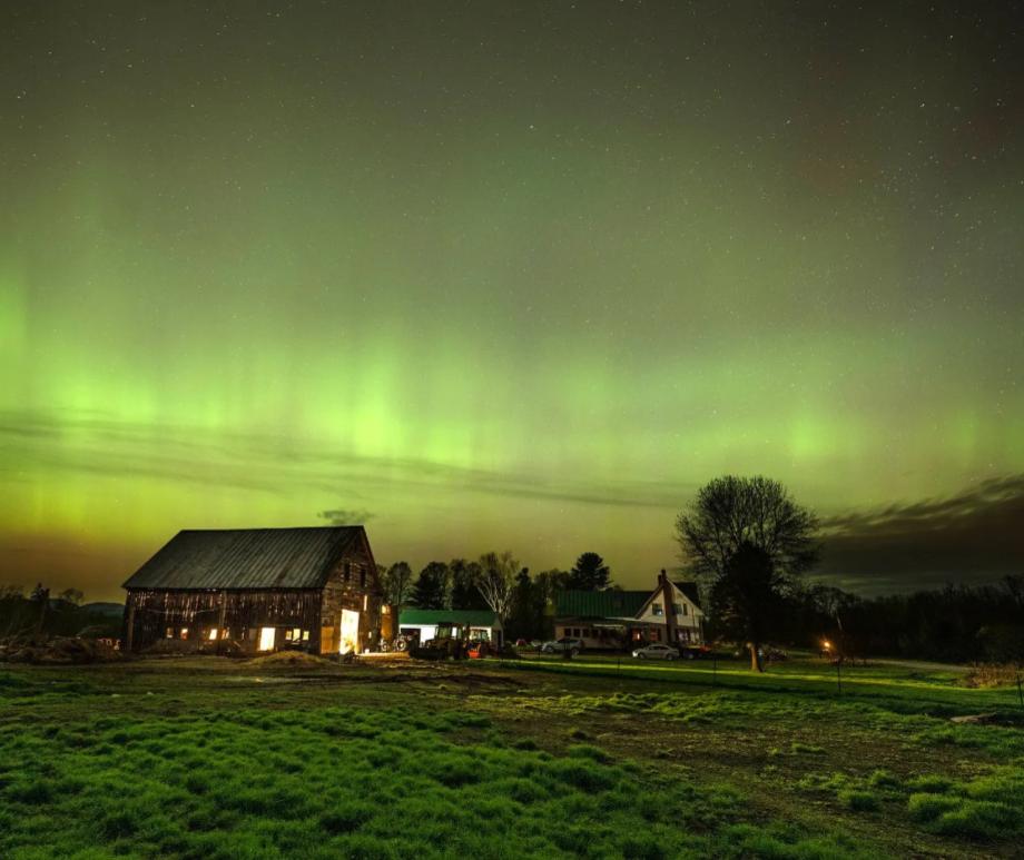 The northern lights fill the sky with green ribbons of electrical charged particles over the barn and pastures at Greaney's Turkey Farm in Mercer, Maine on May 11, 2024