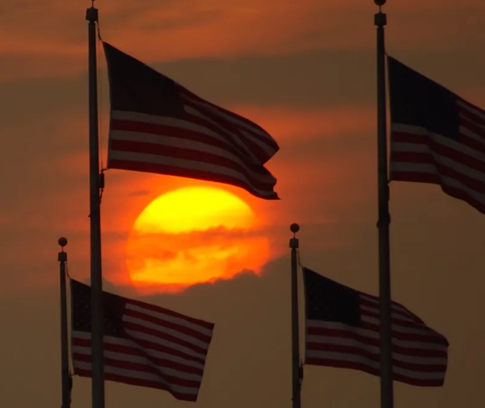 US flags in DC wave with a sunset behind